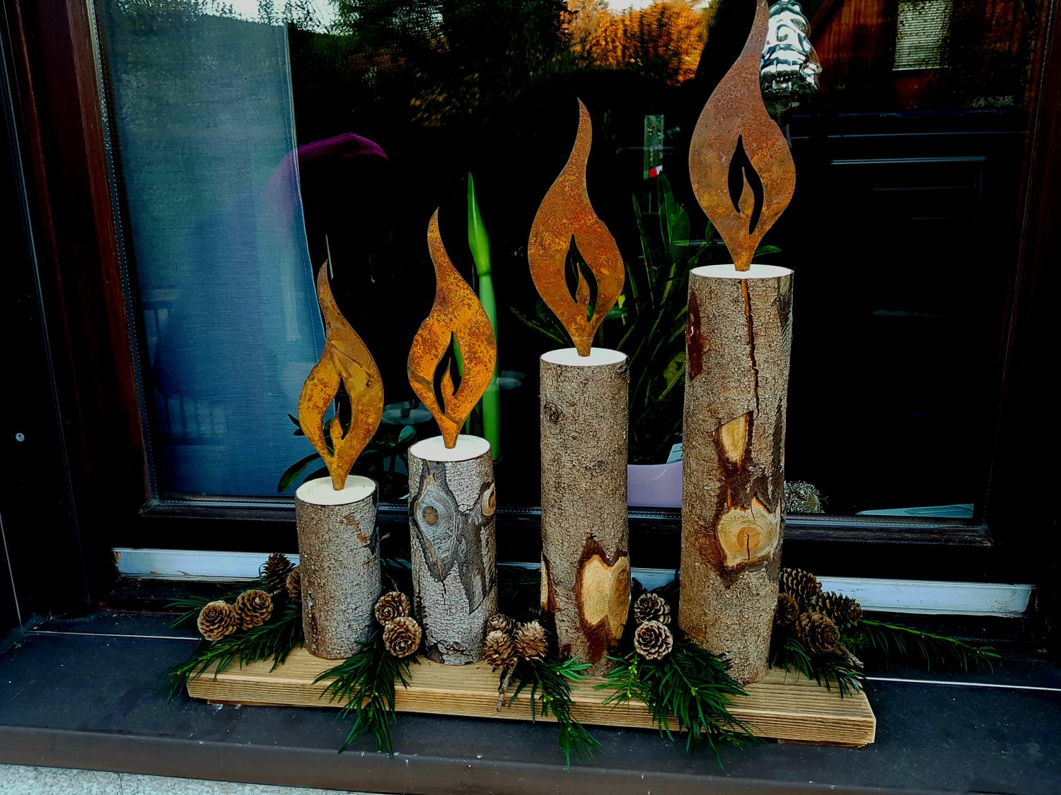 Adventskerzen auf Altholzbrett mit Edelrostflammen